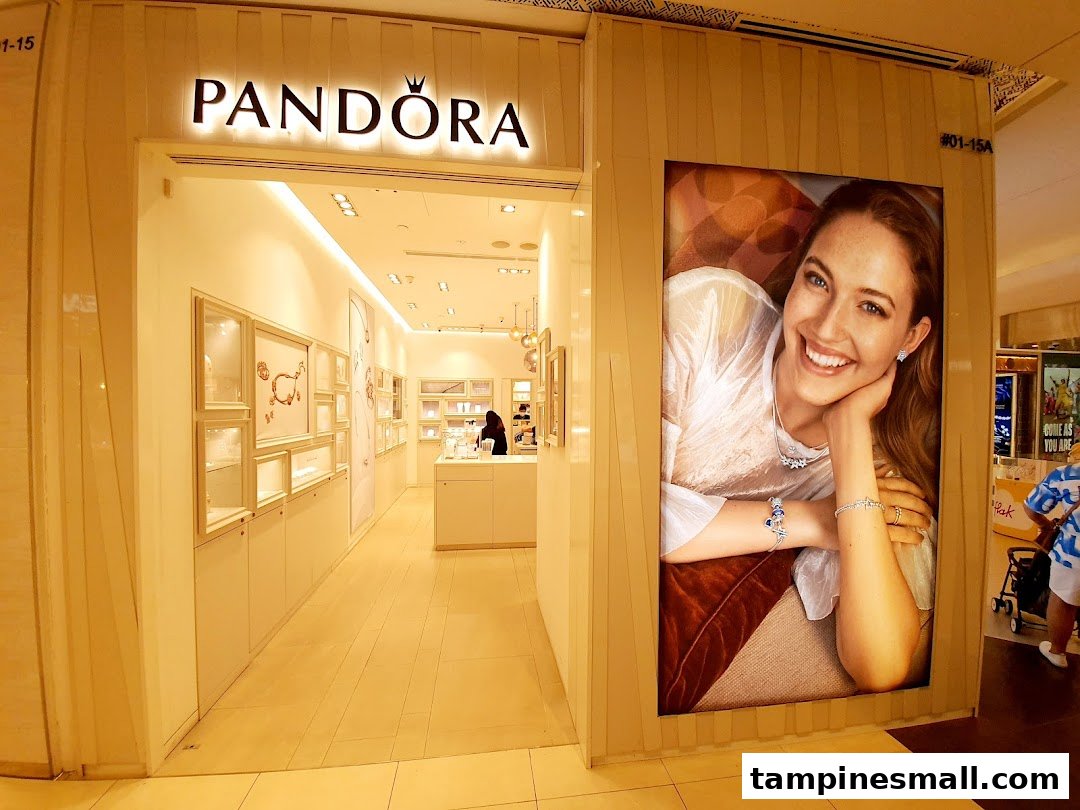The illuminated entrance of a Pandora jewelry store featuring a large promotional display.