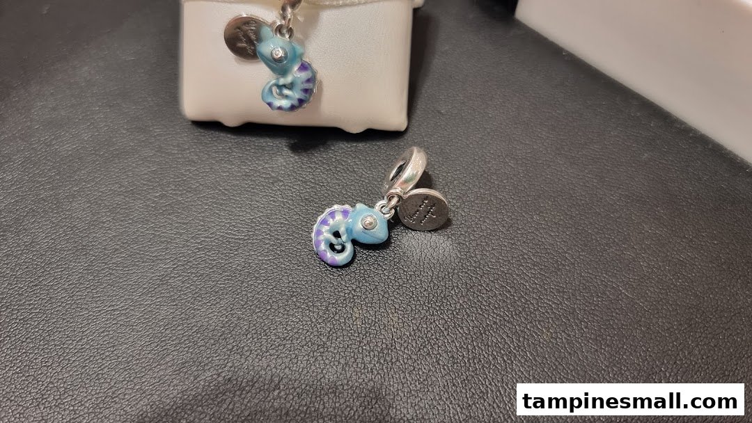 Two colorful chameleon-shaped charms from Pandora, one on a display box and one on a dark surface.
