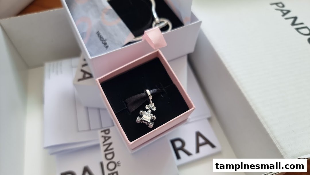 A detailed close-up of a Pandora charm in its signature pink box, surrounded by branded packaging.