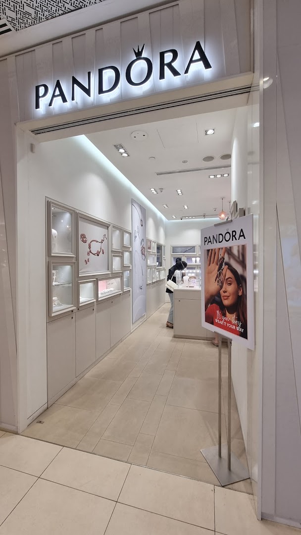 The bright entrance of a Pandora jewelry store, showcasing display cases and a customer browsing.