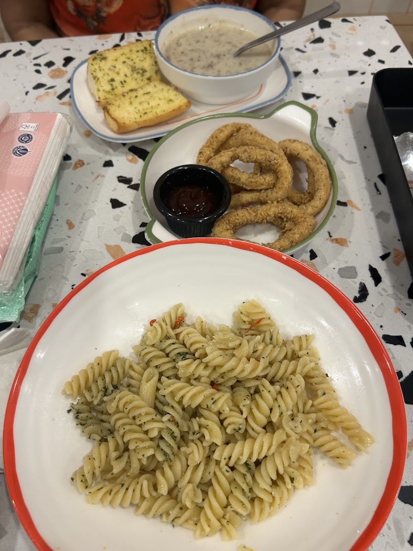A table spread featuring pasta, onion rings, garlic bread, and mushroom soup from PastaMania.