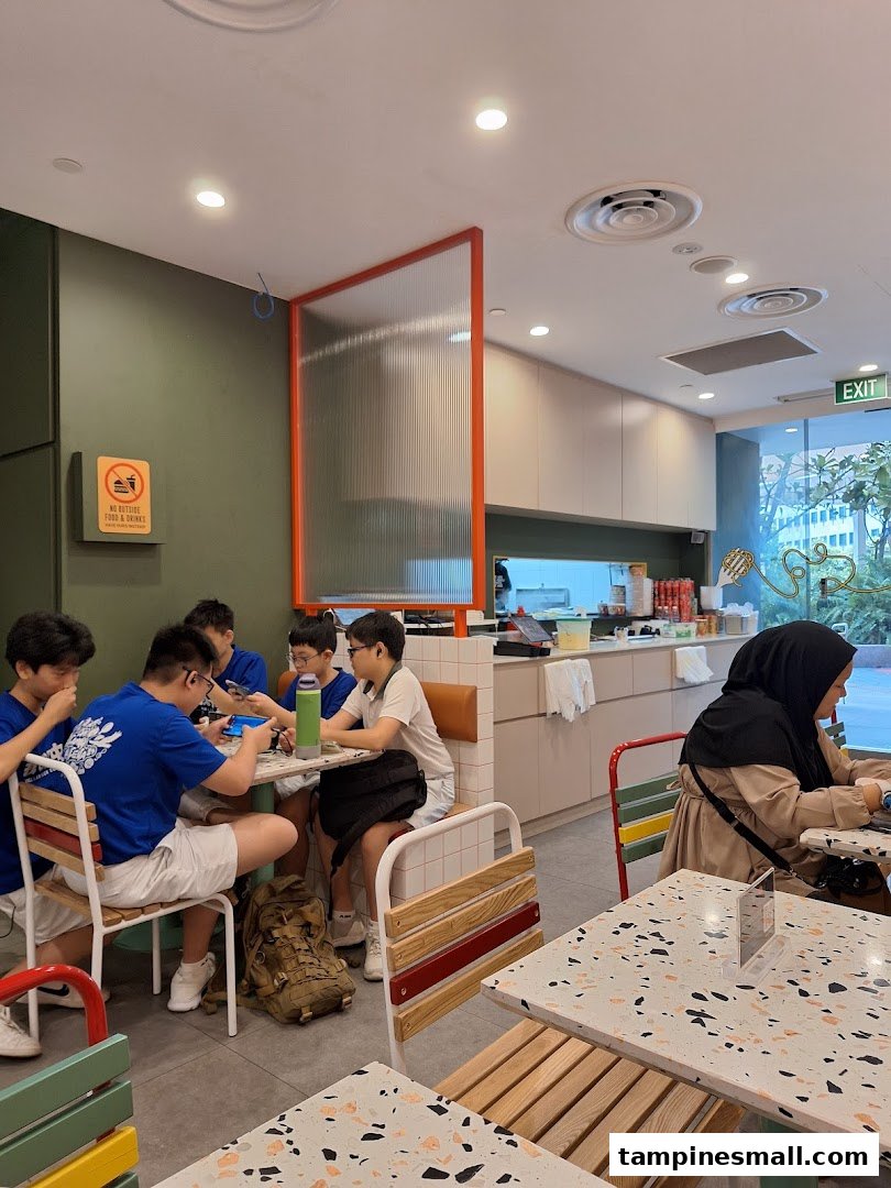 Customers enjoy casual dining in PastaMania's modern interior, featuring colorful seating and a relaxed atmosphere.