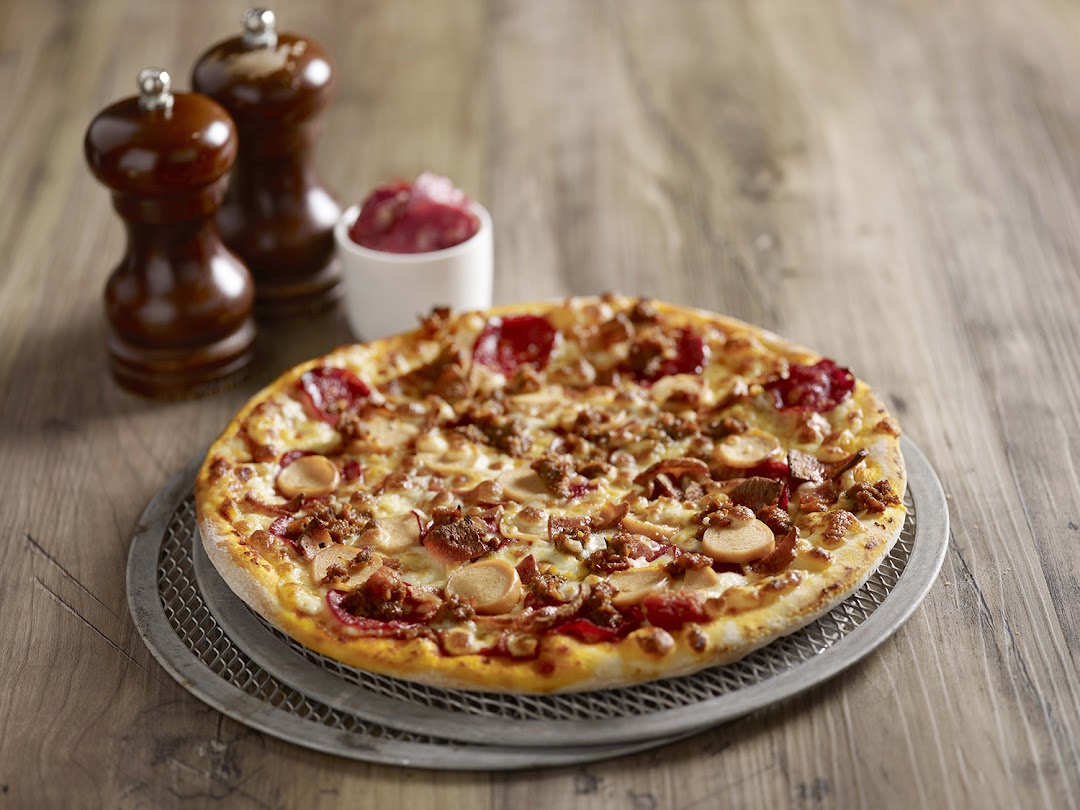 A delicious, fully loaded pizza with various toppings on a wooden table.