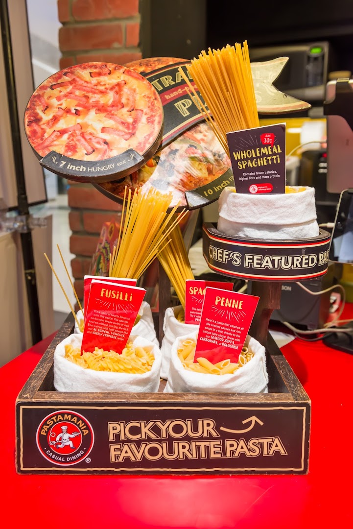 A vibrant in-store display showcasing various pasta types and pizza size options at PastaMania.