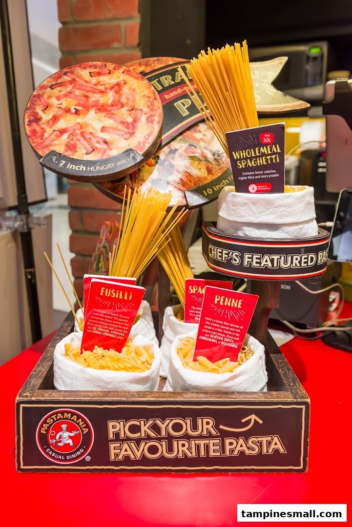 A vibrant in-store display showcasing various pasta types and pizza size options at PastaMania.