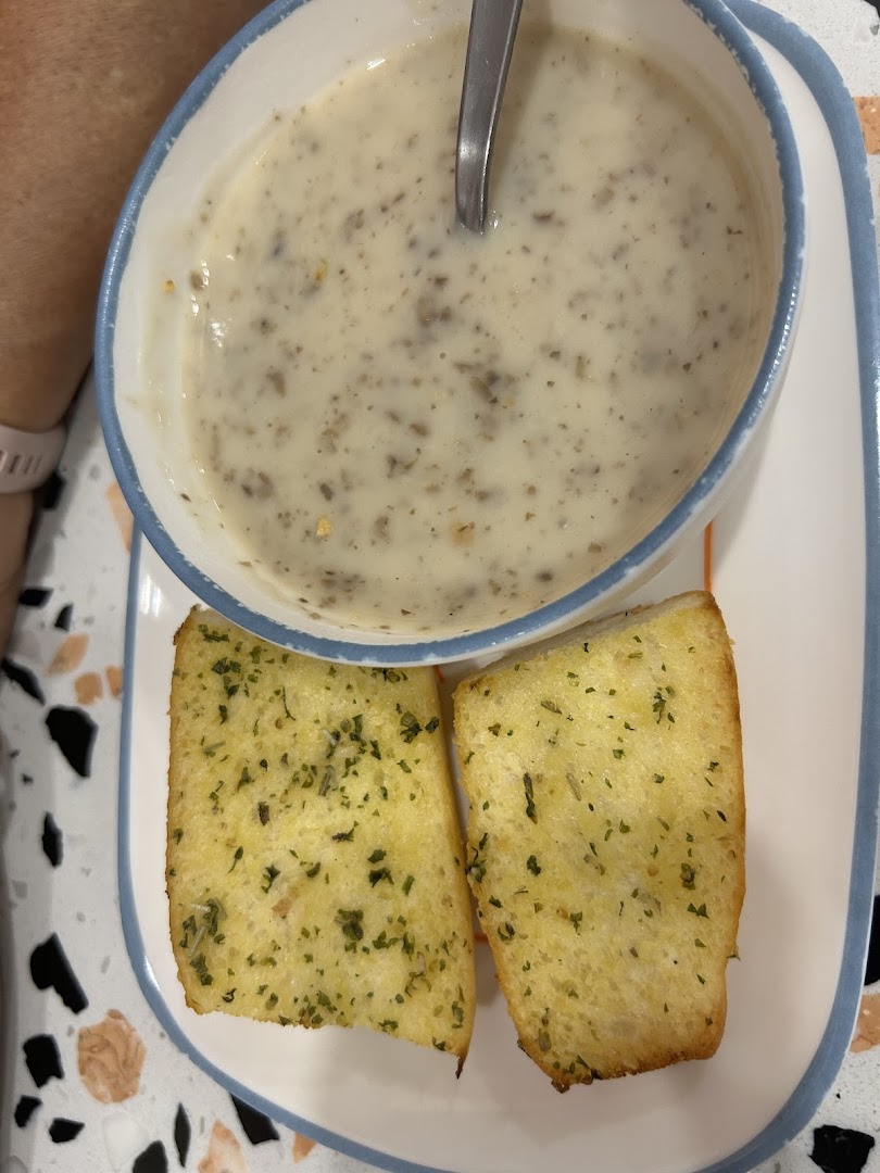 A creamy mushroom soup served with two slices of golden garlic bread on a plate.
