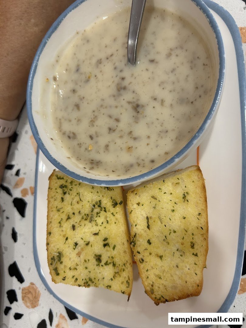A creamy mushroom soup served with two slices of golden garlic bread on a plate.