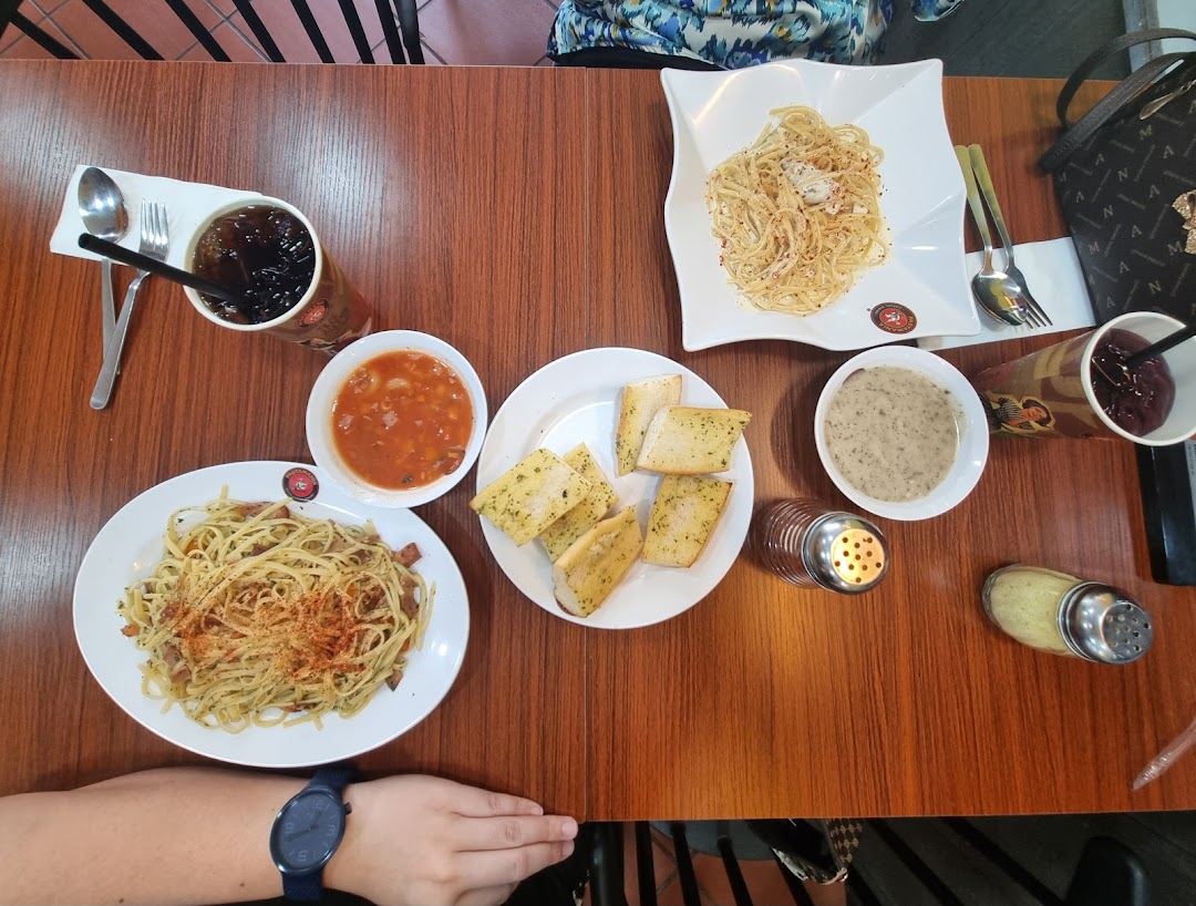 An overhead view of a table laden with pasta dishes, garlic bread, soups, and drinks.