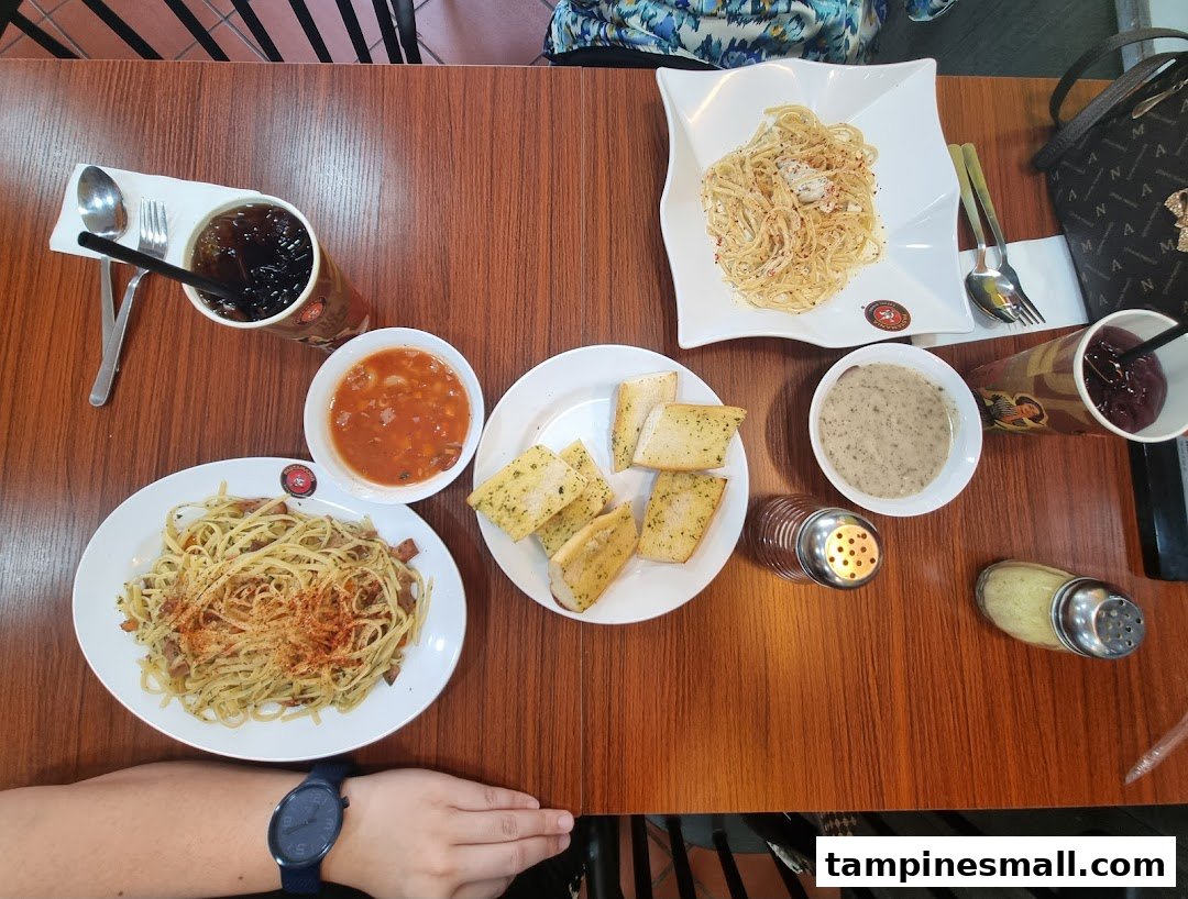 An overhead view of a table laden with pasta dishes, garlic bread, soups, and drinks.