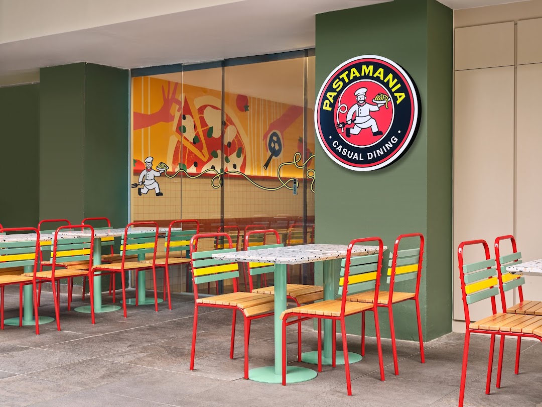 Exterior view of PastaMania with outdoor seating and vibrant branding.