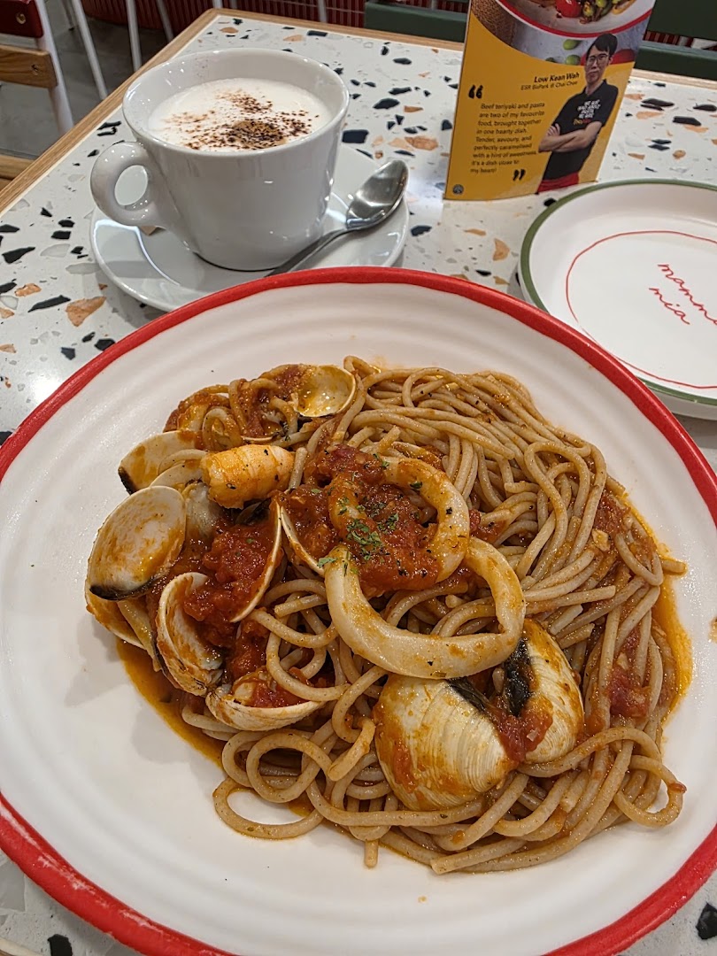 A close-up of a delicious seafood pasta dish and a coffee cup on a table.