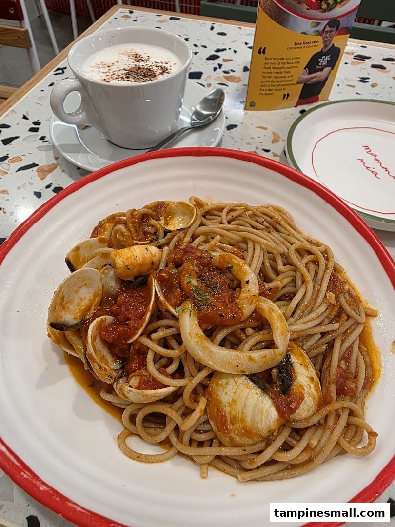 A close-up of a delicious seafood pasta dish and a coffee cup on a table.