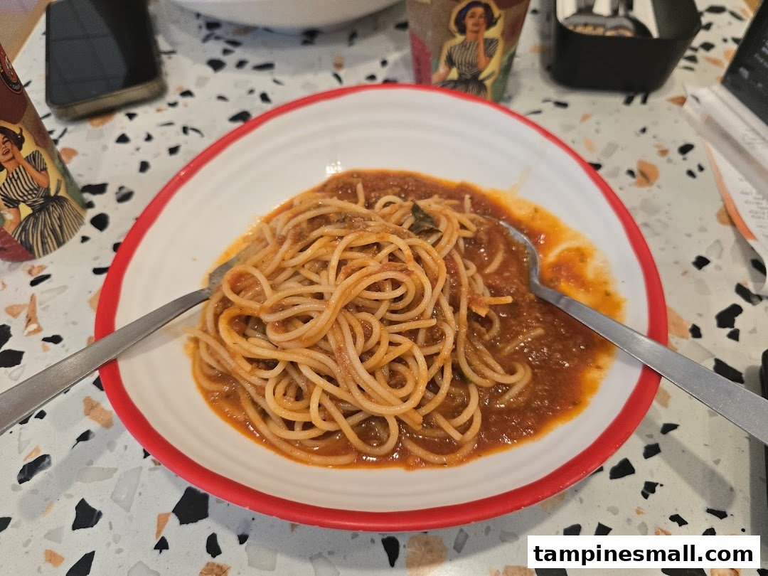 A close-up of a plate of spaghetti with rich tomato sauce on a patterned table.