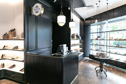 Interior view of PAZZION Tampines Mall, showcasing stylish shoes on display shelves and a central counter.