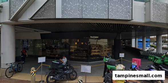 The storefront of PAZZION footwear boutique at Tampines Mall, with delivery riders parked outside.