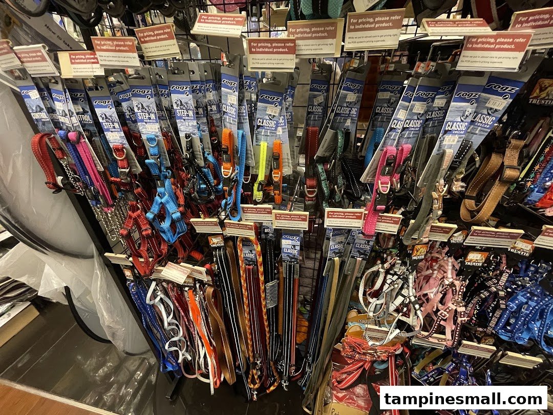 A display rack filled with various colorful pet collars, leashes, and harnesses.