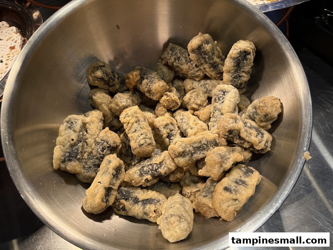 A large metal bowl filled with golden-brown, crispy fried seaweed rolls (gim-mari).
