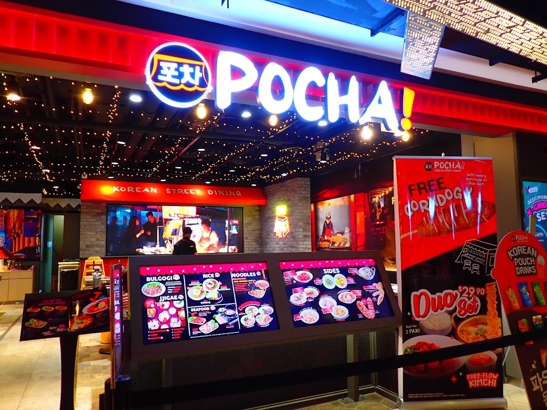 The vibrant red and neon-lit storefront of POCHA! Korean Street Dining, featuring digital menu displays and promotional banners.