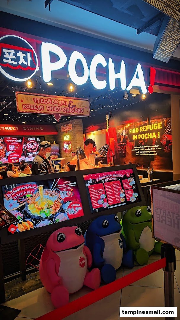 Brightly lit entrance of POCHA! Korean Street Dining, featuring signage, menu displays, and colorful frog mascots.
