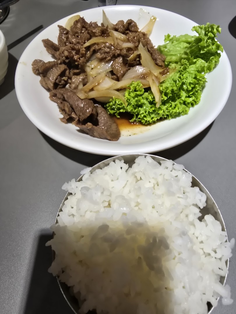 A delicious plate of Korean bulgogi-style beef with onions and fresh lettuce, served with a bowl of white rice.