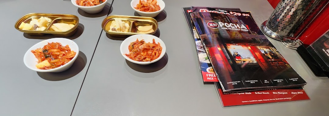 Korean banchan and side dishes on a table with POCHA! Korean Street Dining menus.