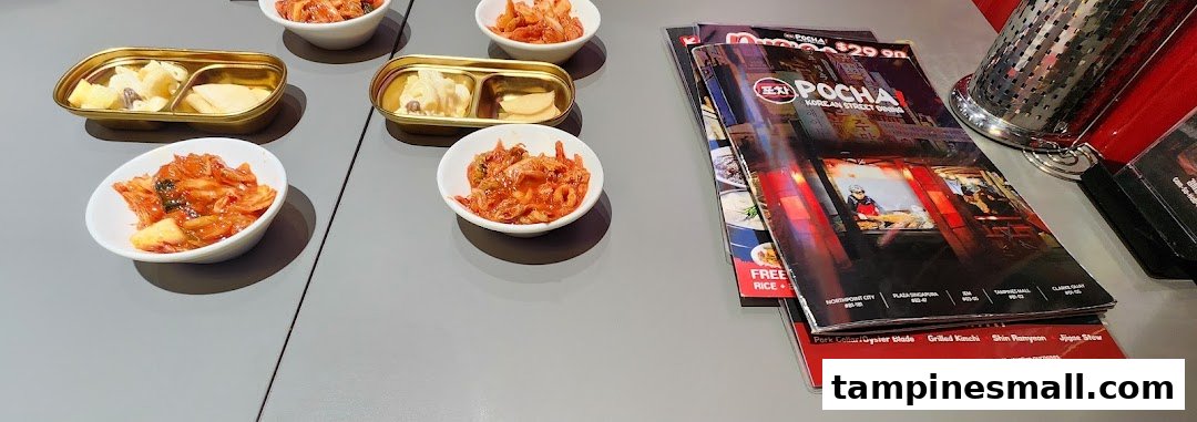 Korean banchan and side dishes on a table with POCHA! Korean Street Dining menus.