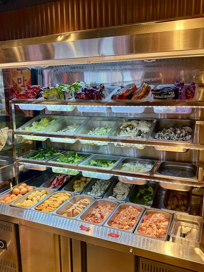 A vibrant display counter showcasing a wide variety of fresh ingredients for custom Korean dishes.