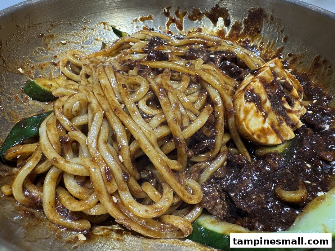 A close-up of Korean black bean noodles (Jajangmyeon) with cucumber and a boiled egg.