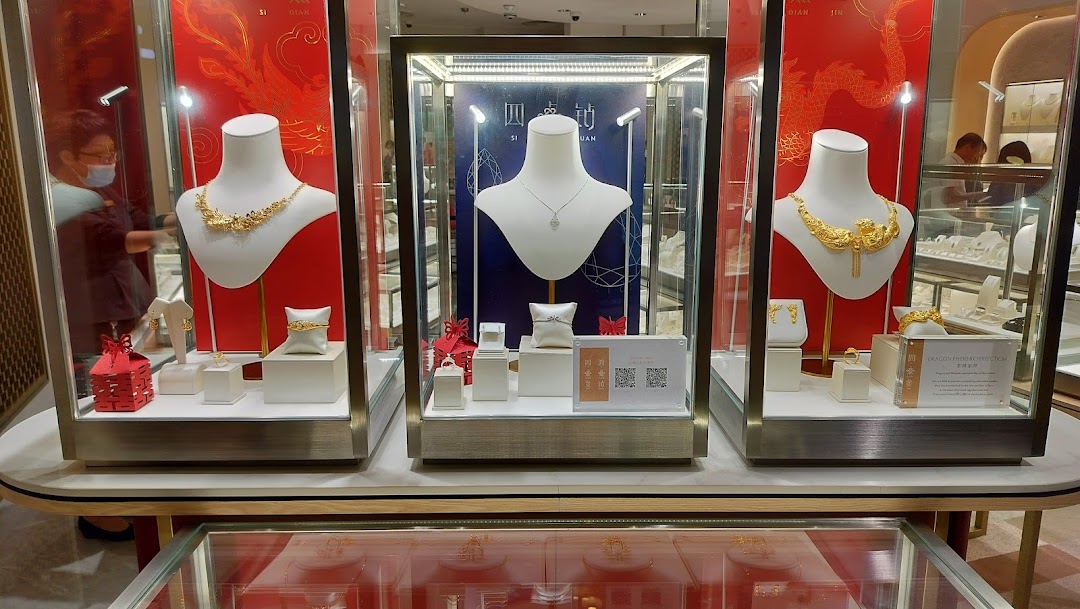 Three illuminated display cases showcase intricate gold and diamond jewelry pieces, including necklaces and rings.