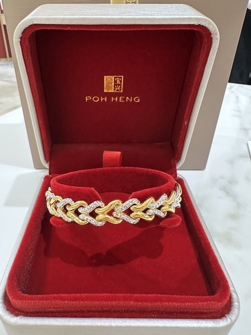 A luxurious gold and diamond bracelet displayed in a red velvet Poh Heng Jewellery box.