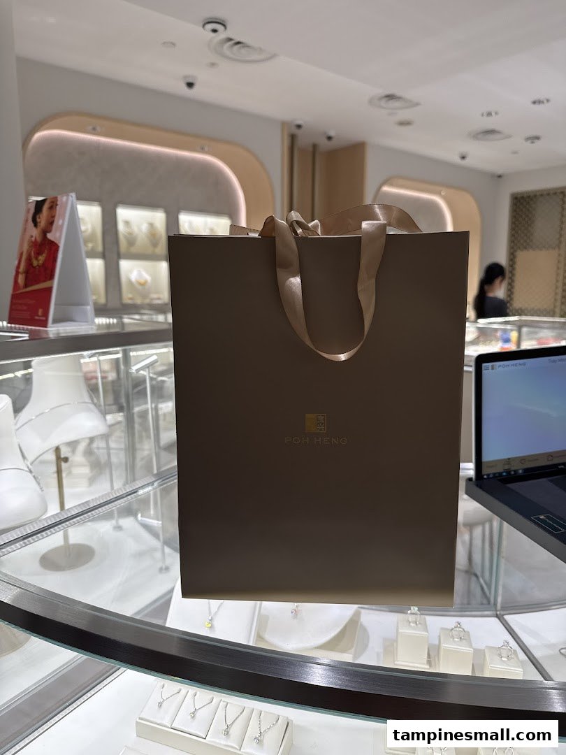 A Poh Heng Jewellery shopping bag sits on a display counter inside the elegant store, showcasing fine jewelry.