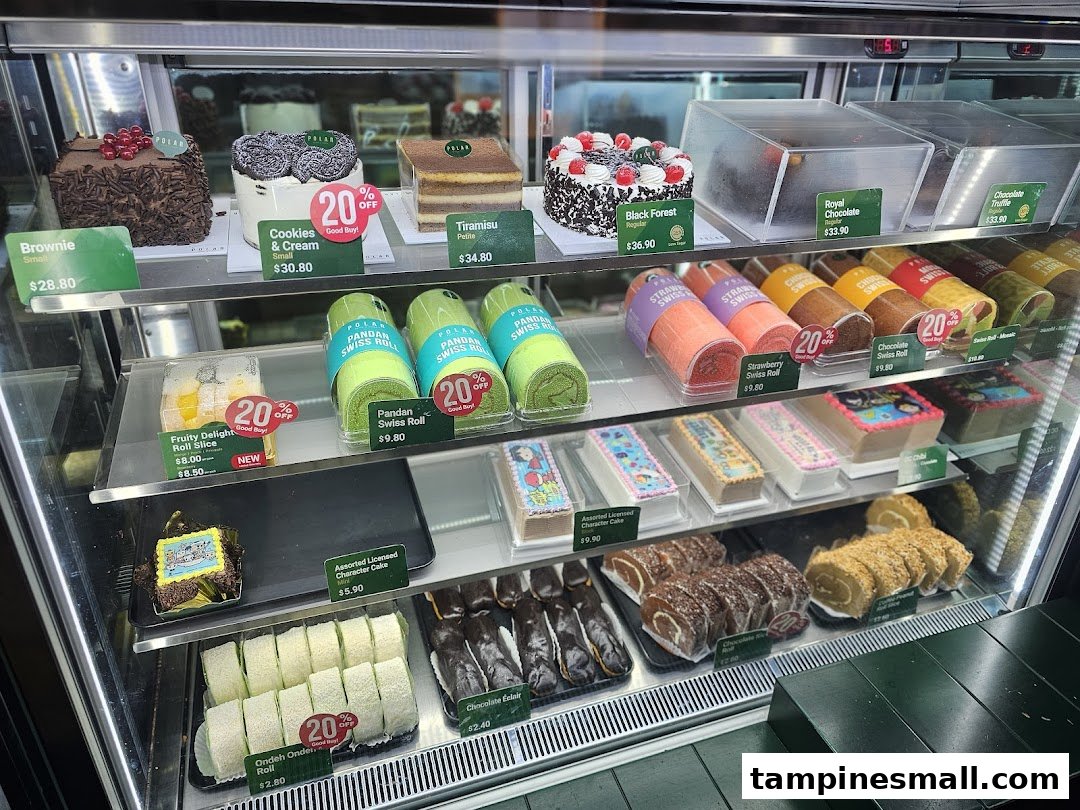 A brightly lit display case showcasing a variety of cakes, swiss rolls, and pastries at Polar Puffs & Cakes.