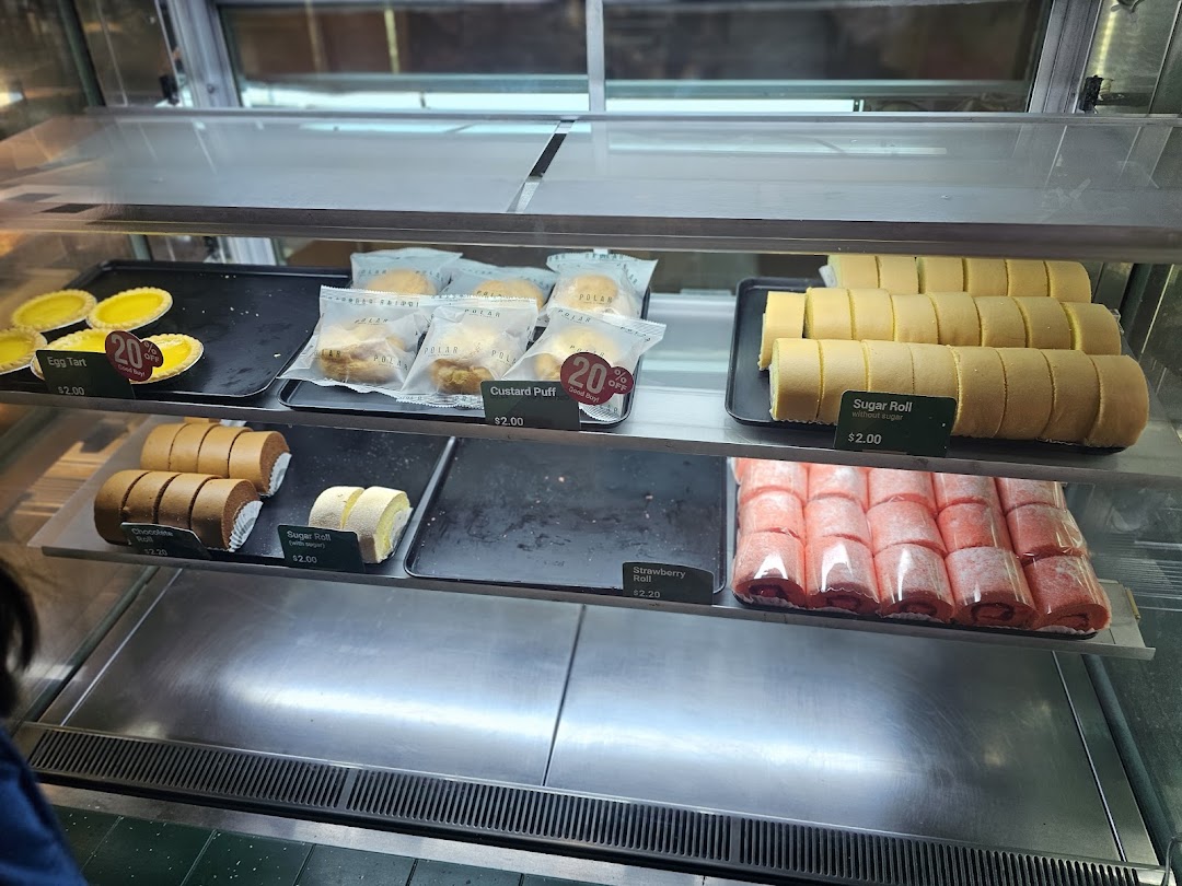 A display case at Polar Puffs & Cakes showcasing a variety of delicious pastries and rolls.