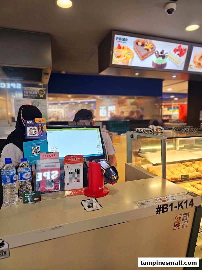 Cashier counter at Polar Puffs & Cakes with staff, payment terminals, and cake display.