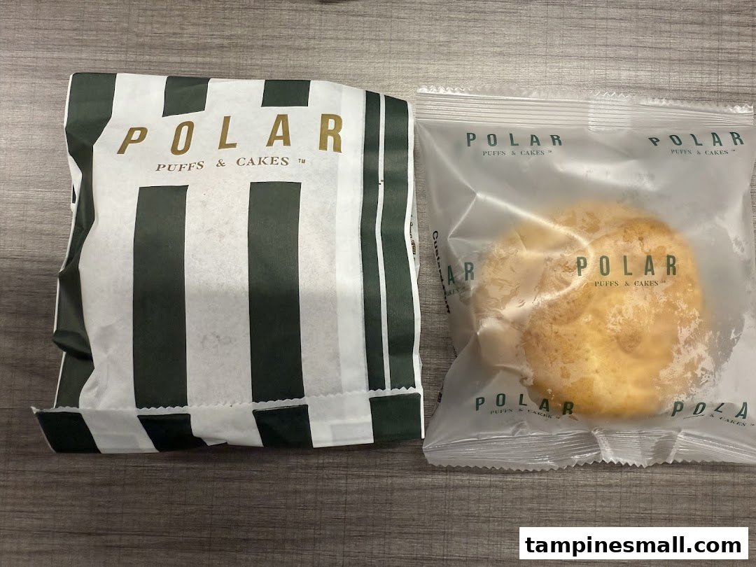 A paper bag and a packaged pastry from Polar Puffs & Cakes on a wooden surface.