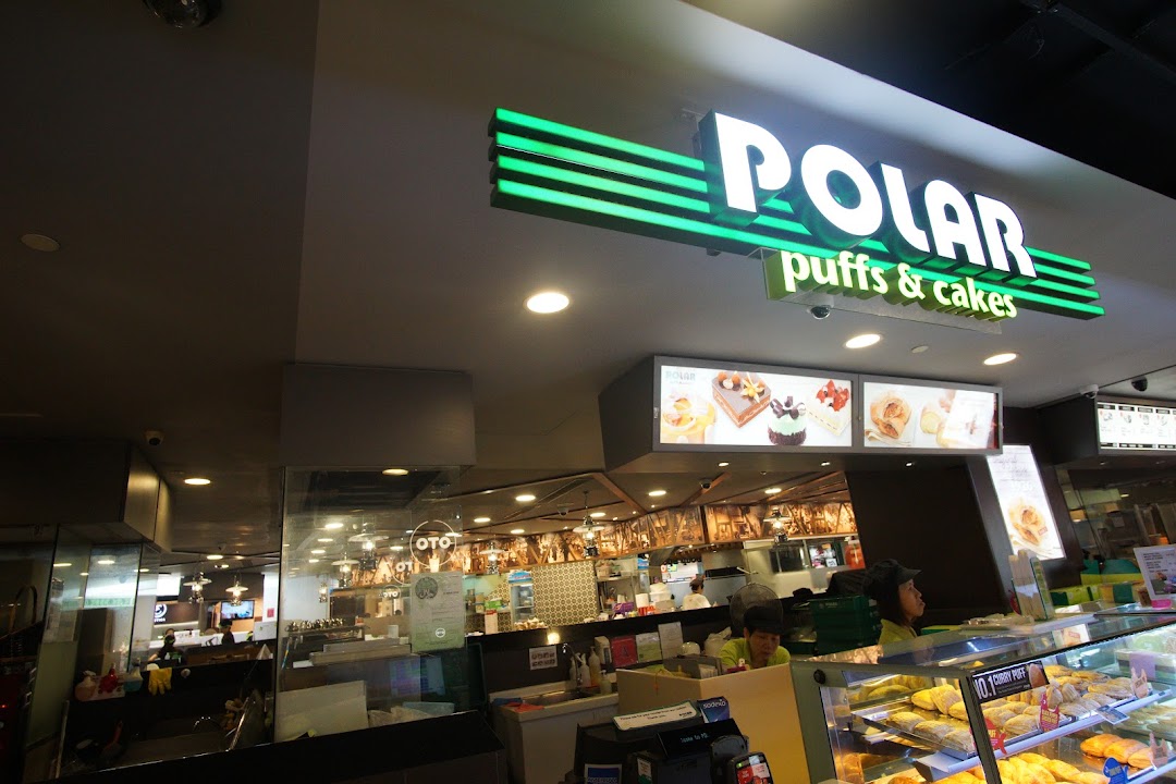 An interior view of Polar Puffs & Cakes, showcasing display cases filled with pastries and the illuminated shop sign.