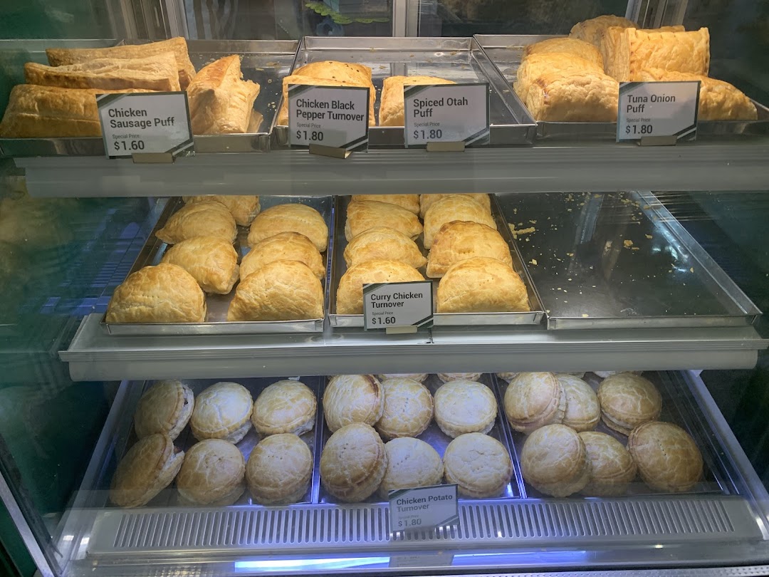 A display case filled with various freshly baked puffs and turnovers, each with a price label.