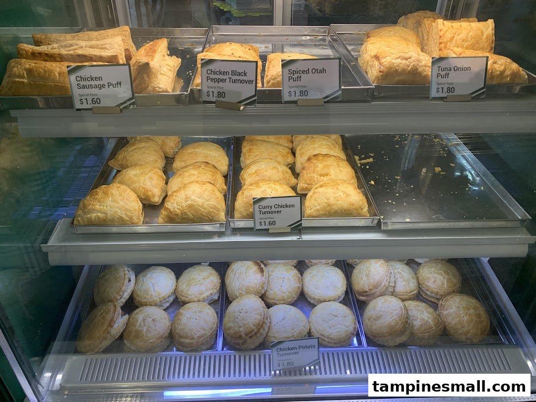 A display case filled with various freshly baked puffs and turnovers, each with a price label.