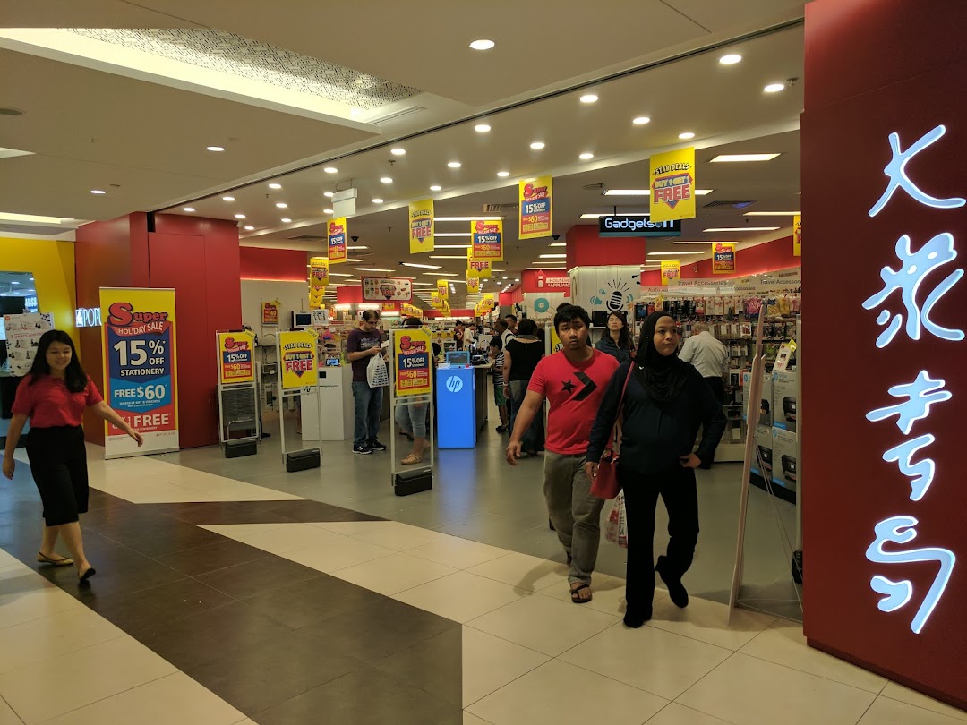 Customers browse books, stationery, and gadgets inside a brightly lit Popular Bookstore.
