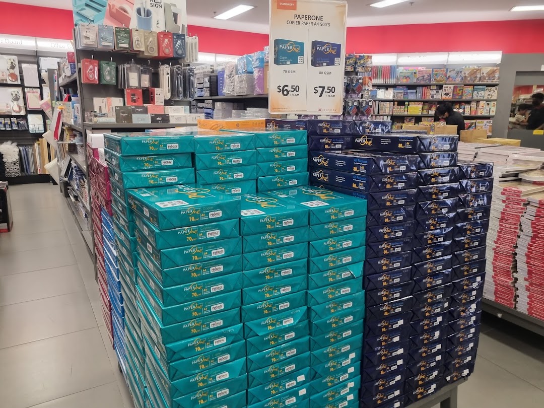 Large stacks of copier paper and stationery items displayed for sale inside a Popular Bookstore.