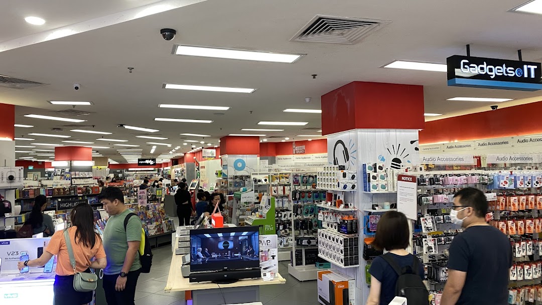 Interior view of POPULAR Bookstore, showcasing books, gadgets, and audio accessories with customers browsing.