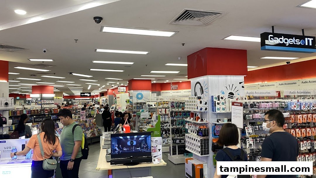 Interior view of POPULAR Bookstore, showcasing books, gadgets, and audio accessories with customers browsing.