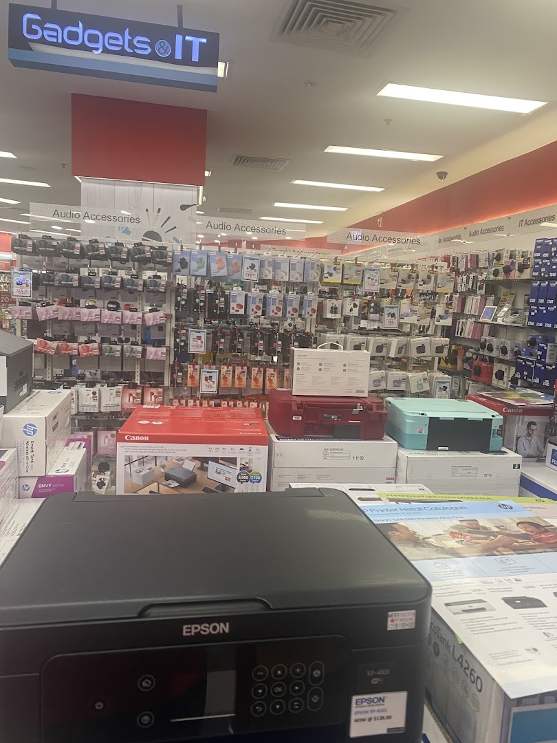 An interior view of a retail store's electronics section, featuring printers and audio accessories.