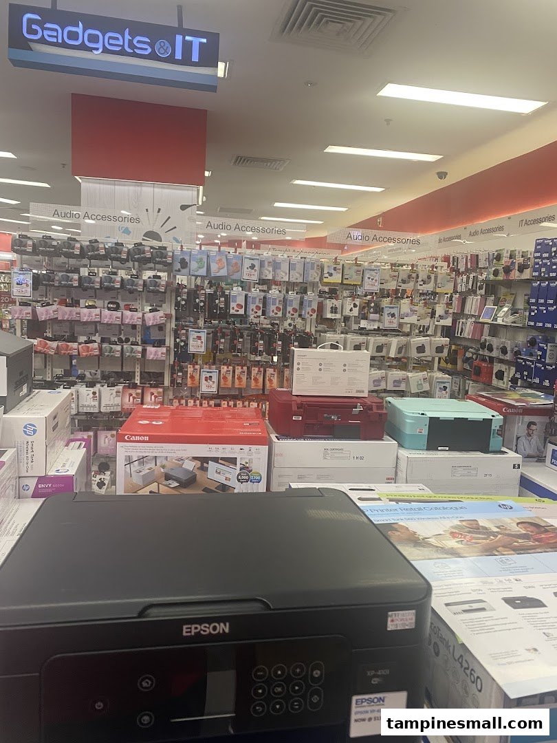 An interior view of a retail store's electronics section, featuring printers and audio accessories.