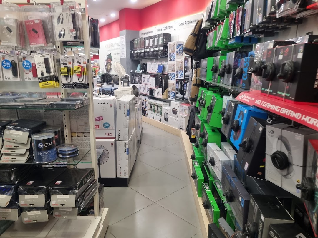 Interior view of a retail store aisle with electronics, home appliances, and computer accessories.