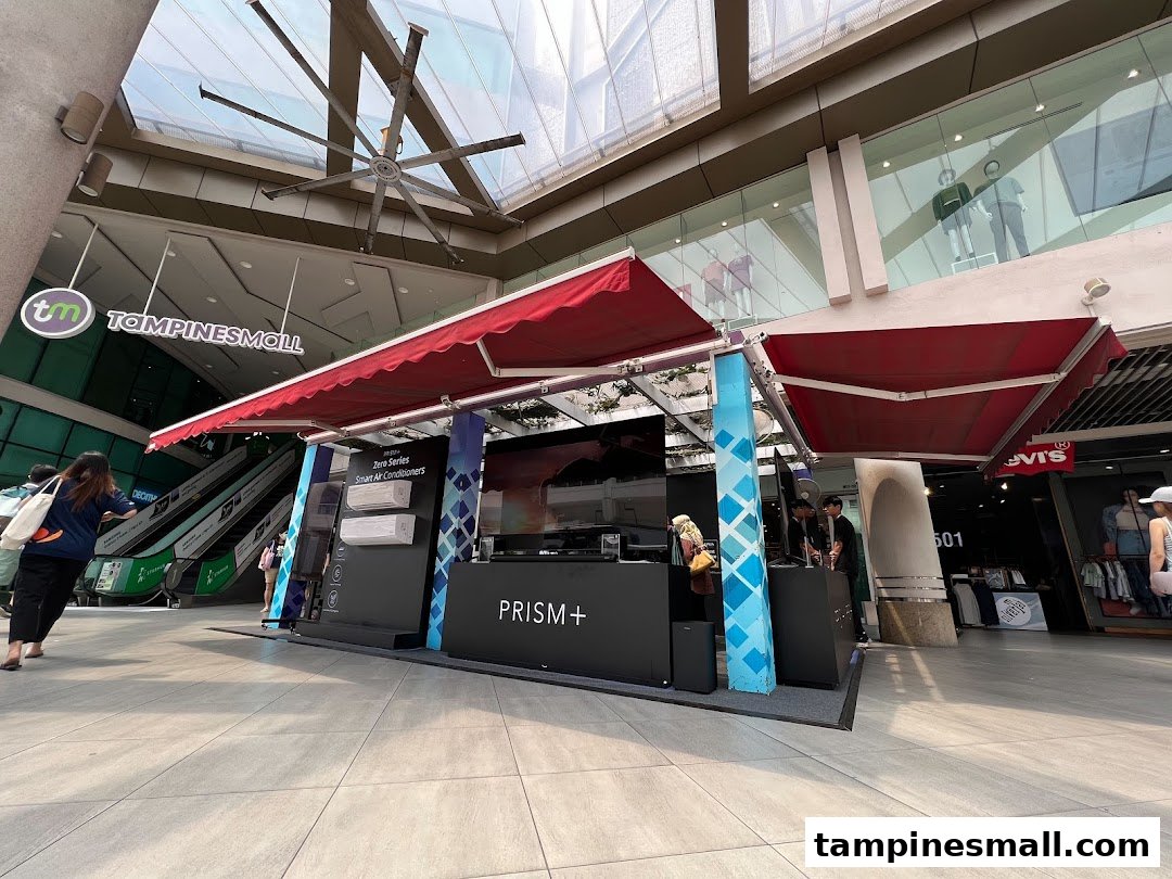 A PRISM+ promotional booth showcasing smart air conditioners and electronics within Tampines Mall.