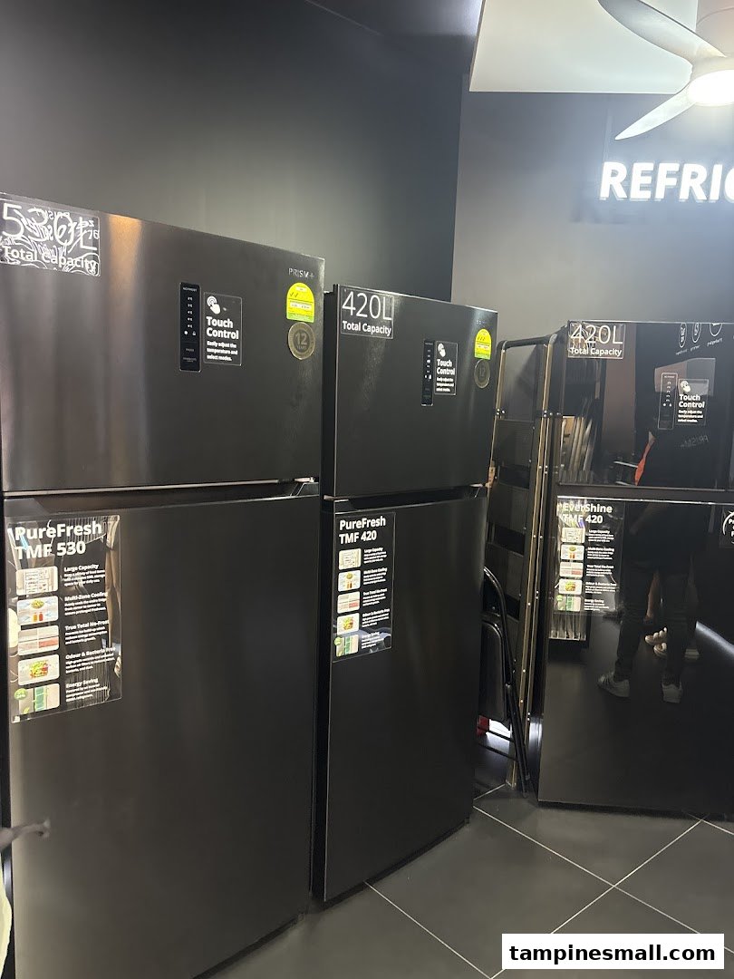 Several modern black refrigerators with touch controls and varying capacities are displayed in a retail store.