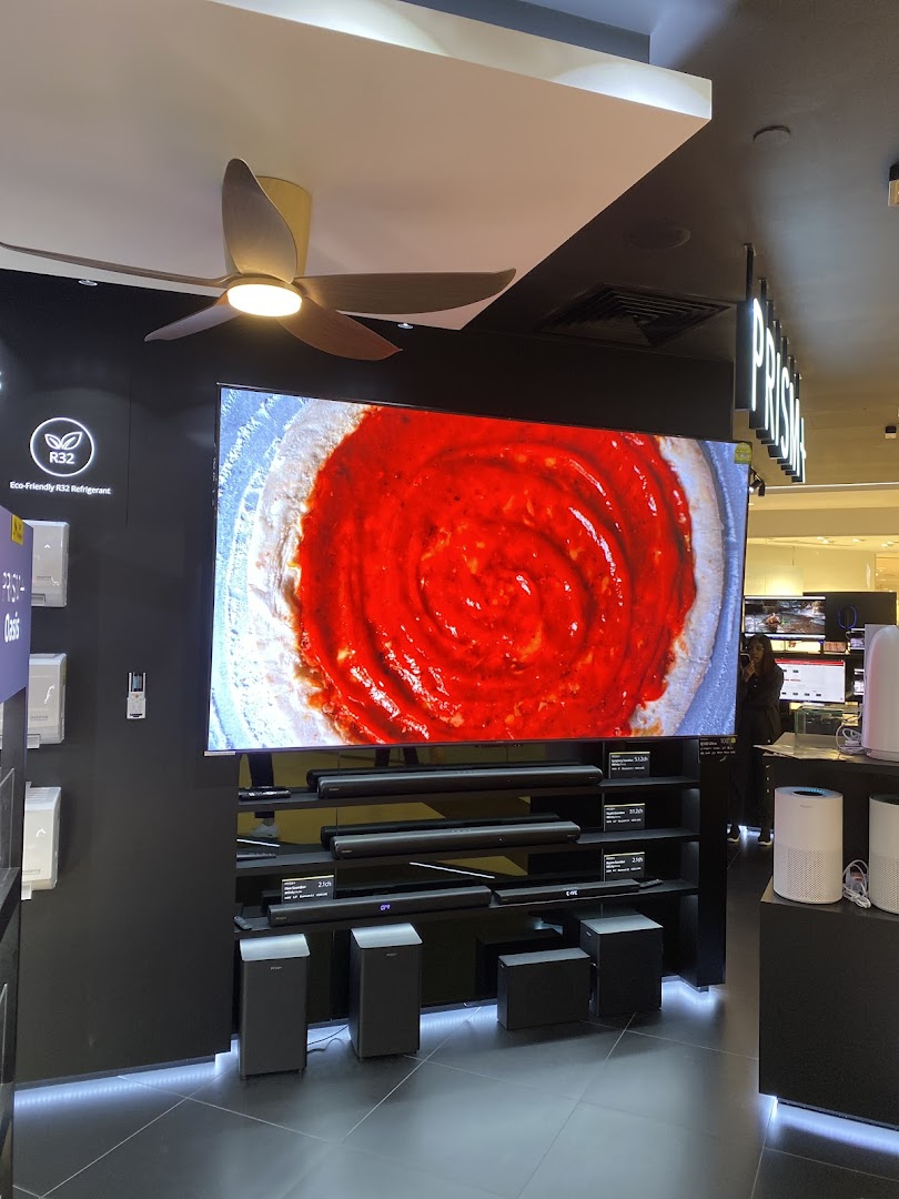 An interior shot of PRISM store showcasing a large TV display, soundbars, and other home electronics.