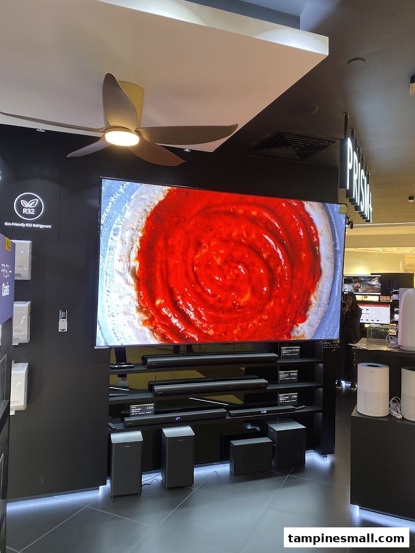 An interior shot of PRISM store showcasing a large TV display, soundbars, and other home electronics.