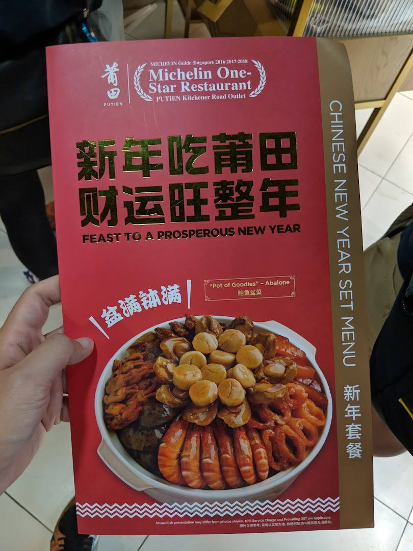 A hand holds a PUTIEN Chinese New Year set menu flyer featuring a 'Pot of Goodies' dish.